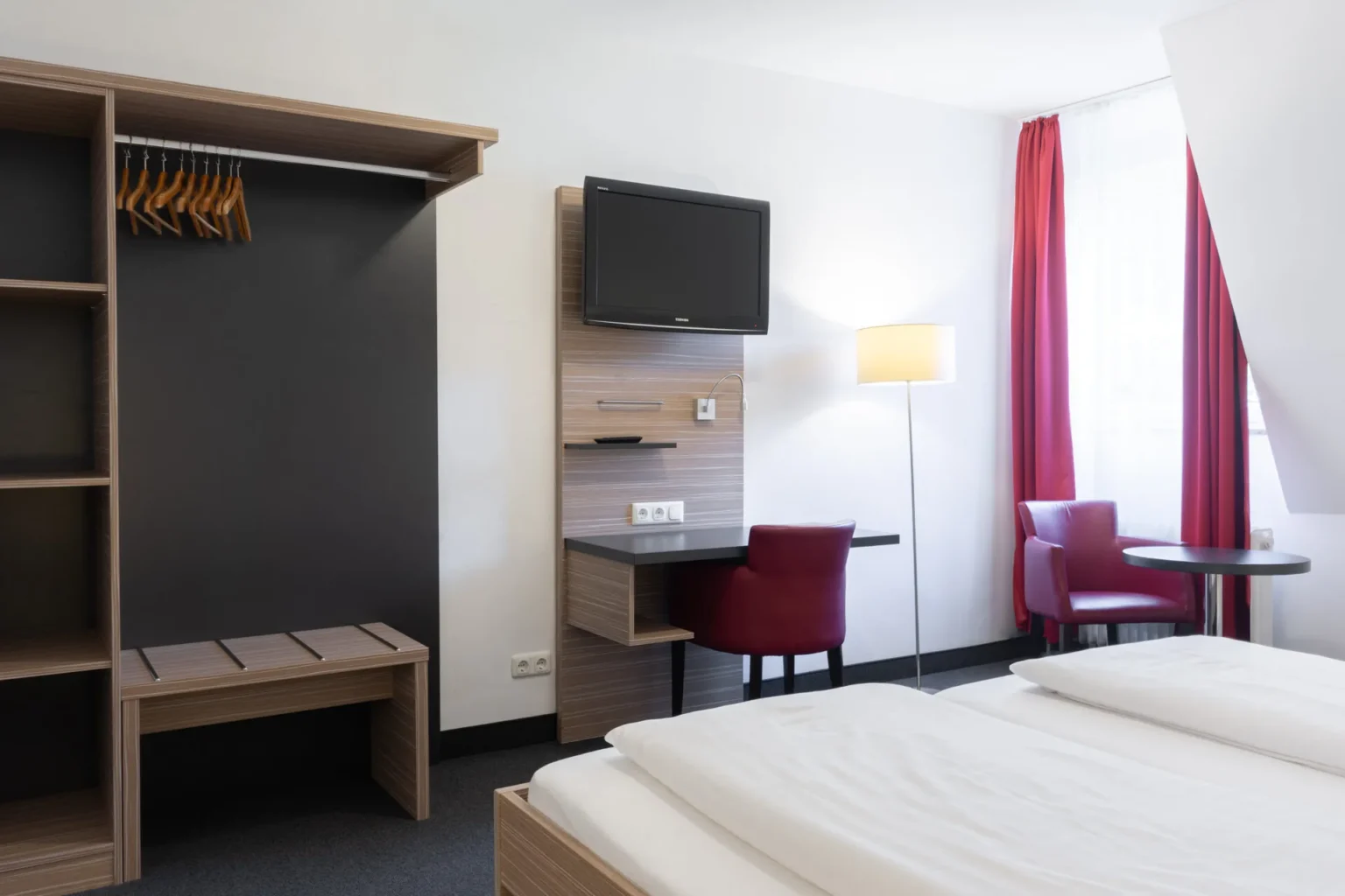 Schreibtisch mit SItzmöglichkeit und Garderobe in einem Hotelzimmer