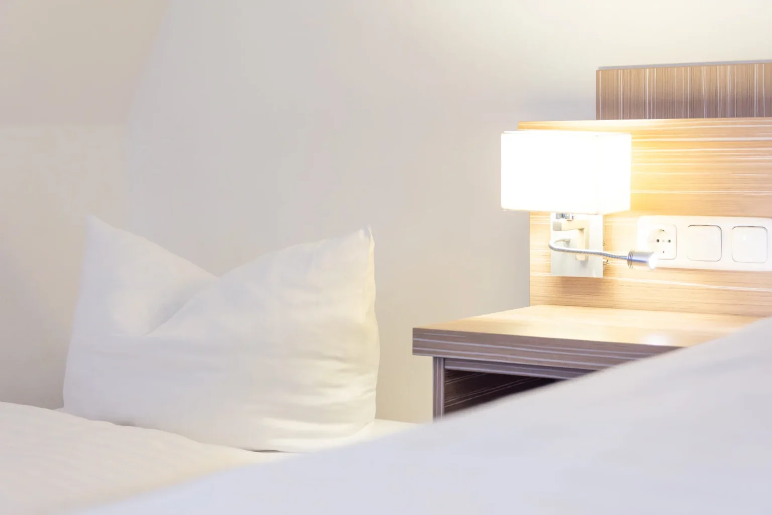 Ansicht auf ein Kissen im Bett neben einem beleuchteten Nachttisch