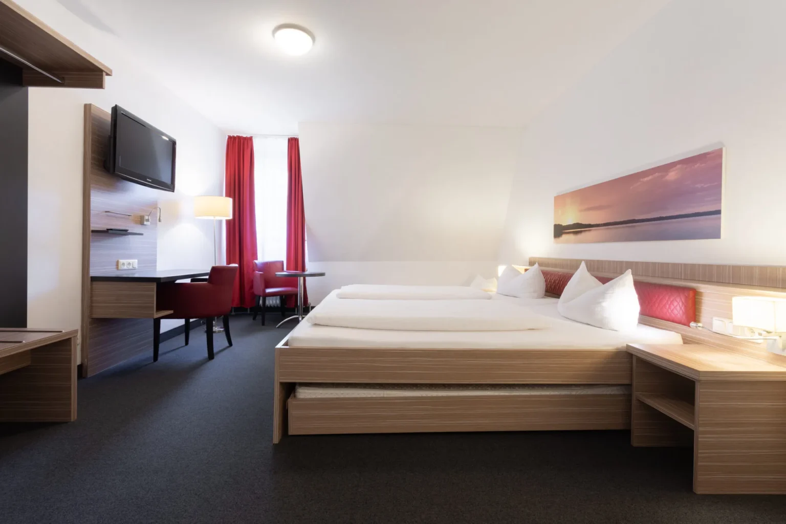 Großes DOppelbett mit ausziehbaren Betten in einem Hotelzimmer mit Schreibtisch und Garderobe