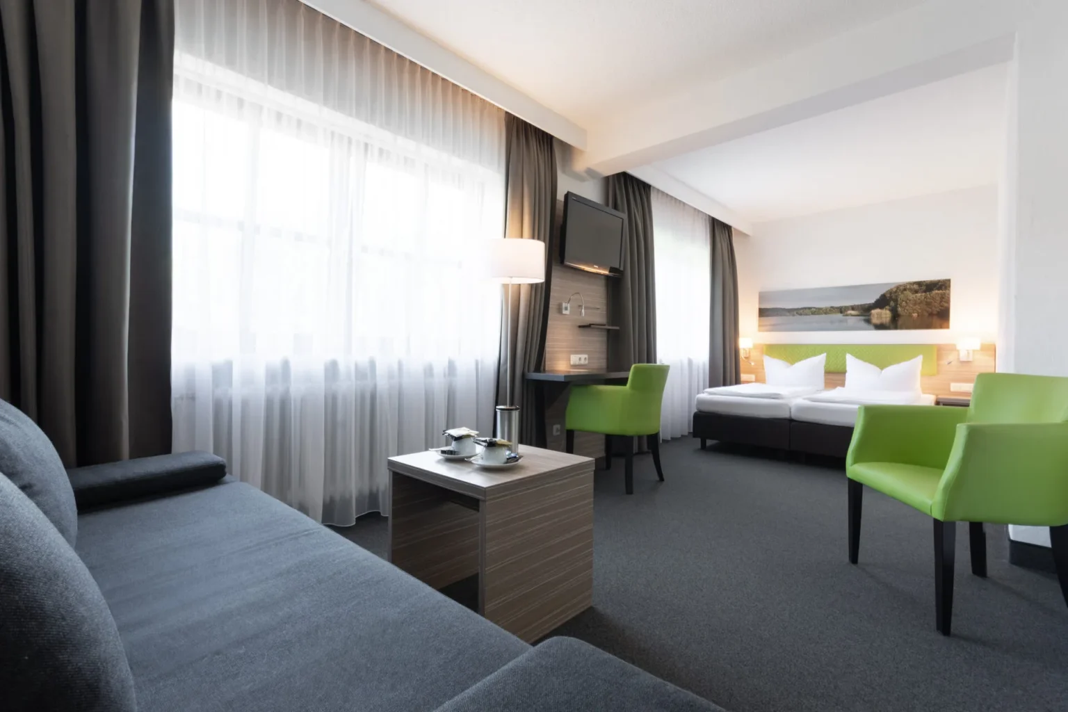 Hotelzimmer mit Sofaecke, Schreibtisch und Doppelbett